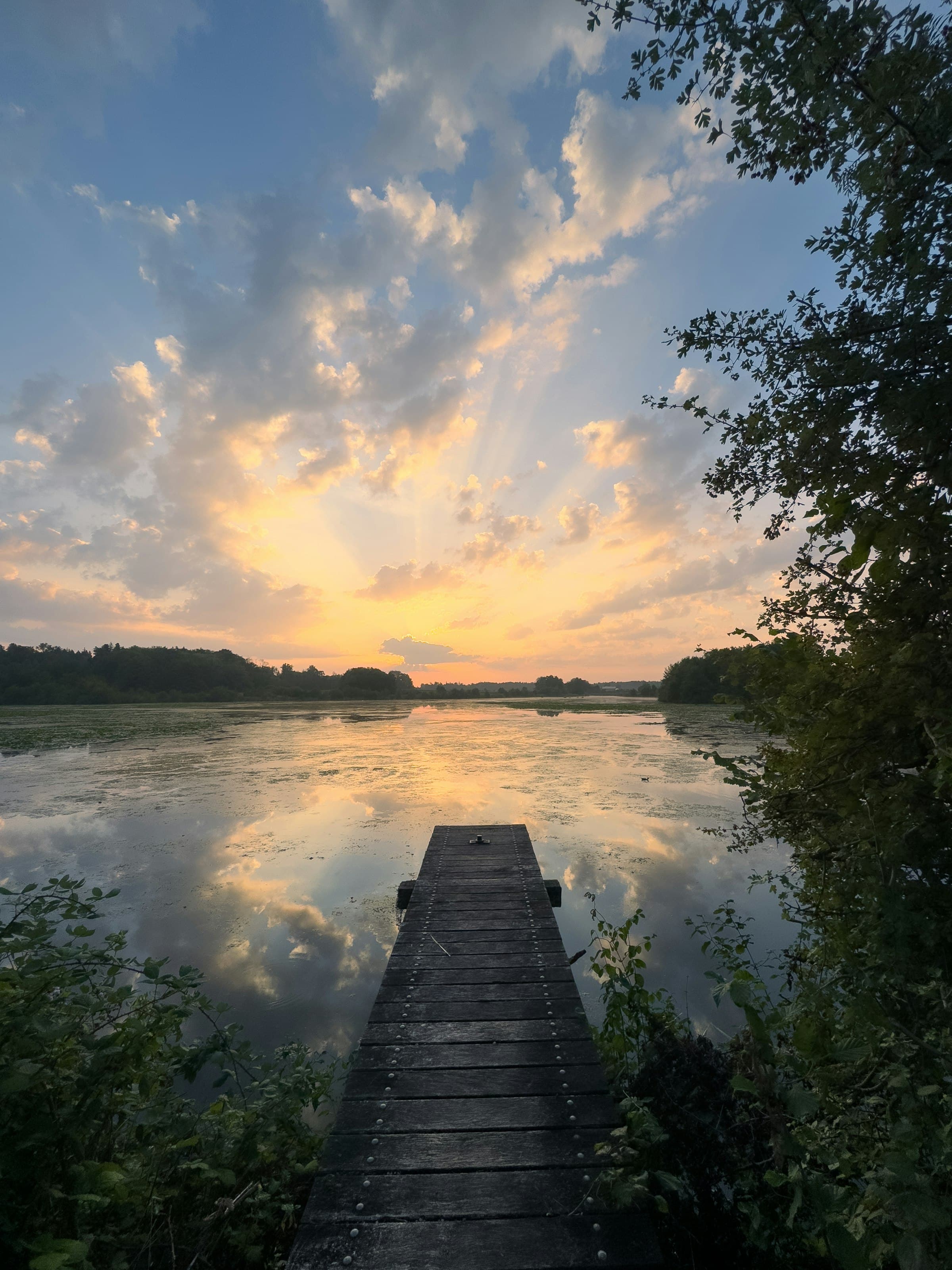 Leerer Holzsteg an einem See im goldenen Abendlicht