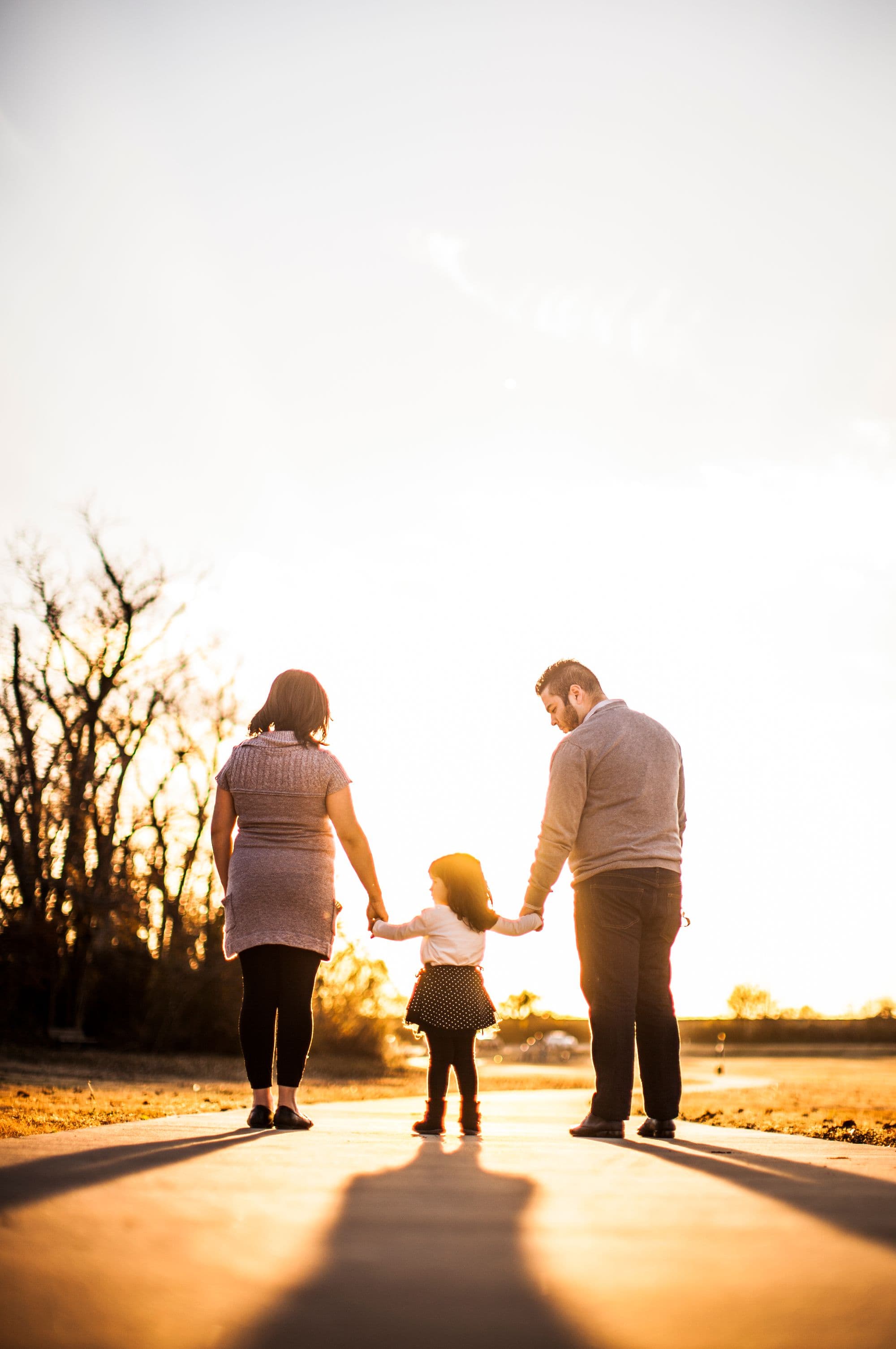 Familie läuft Hand in Hand in die goldene Abendsonne