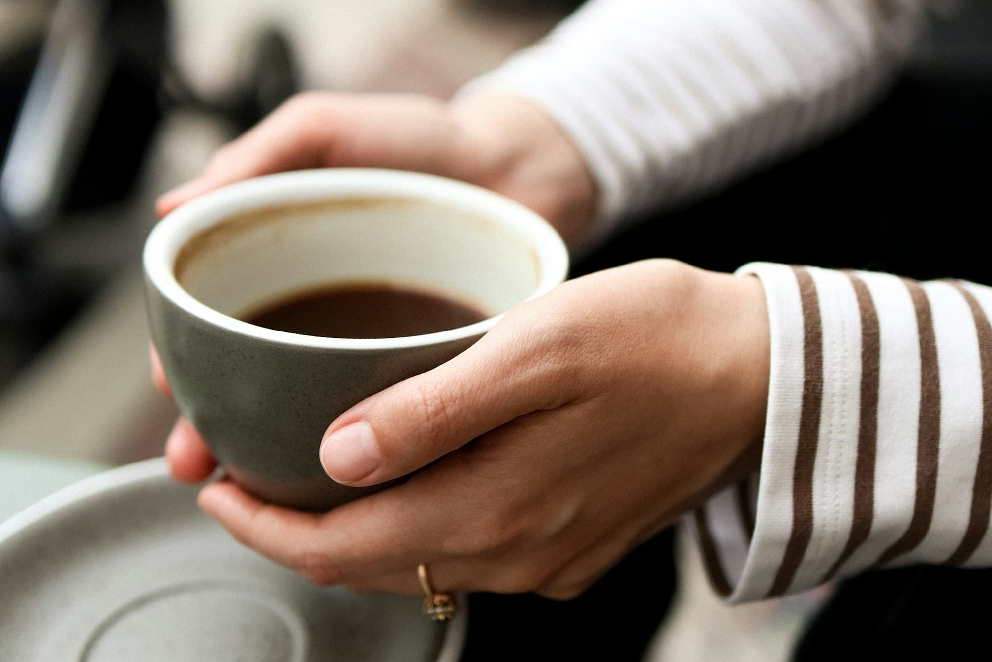 Hände mit warmer Kaffeetasse am Morgen